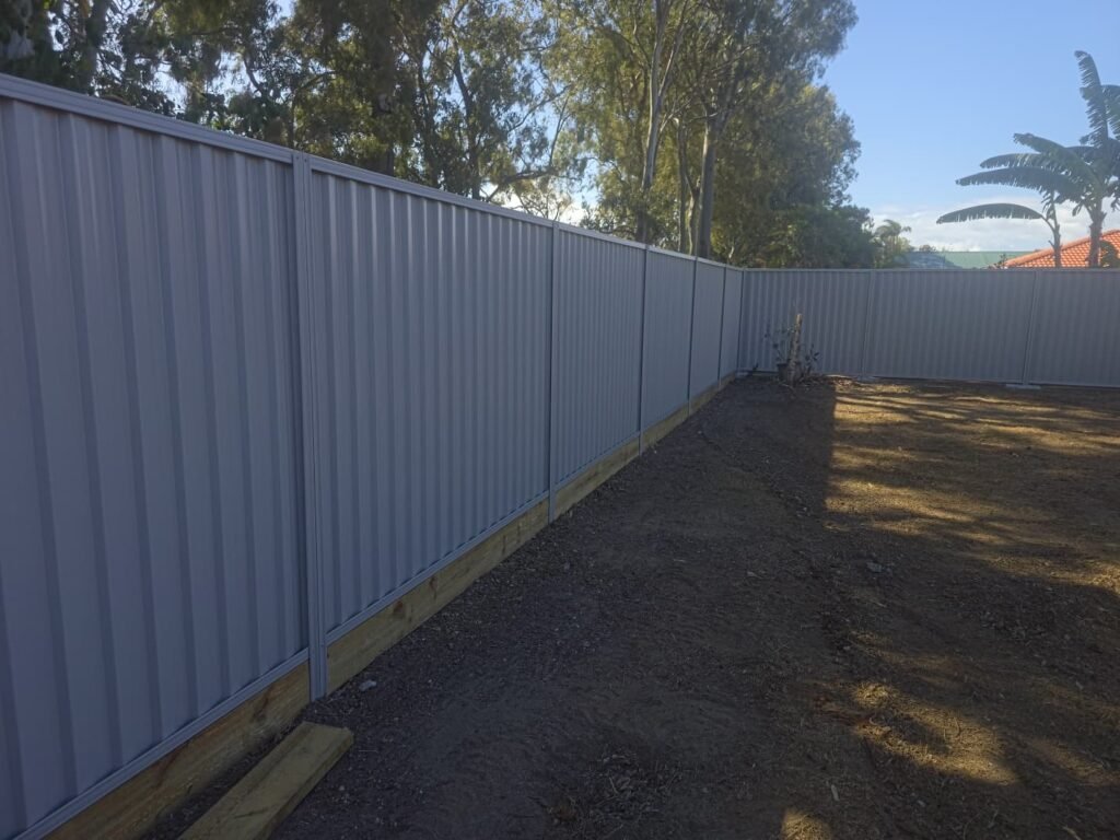 GramLine® steel privacy fence in Birch around a back yard corner, panels, posts and rails in matching colour, supplied in kit form by Accolade Fencing Deception Bay
