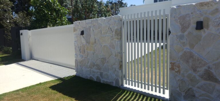 Surfmist RAD batten pedestrian gate set between stone pillars with the matching sliding driveway gate beyond, 40x40 aluminium battens, manufactured by Accolade Fencing