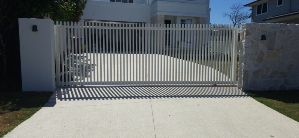 RAD batten aluminium sliding gate in Surfmist powder coat across a driveway, 40x40 battens between a rendered pillar and a stone pillar, manufactured by Accolade Fencing Deception Bay