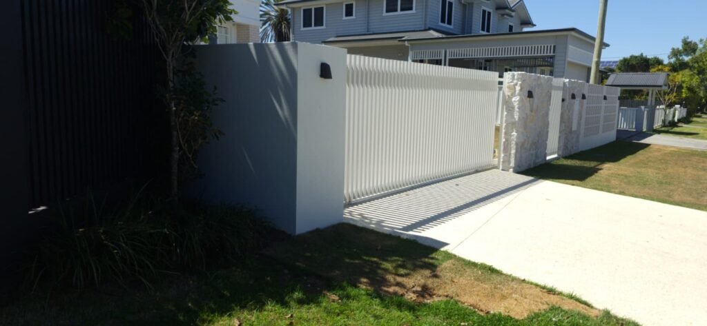 RAD batten sliding gate in Surfmist viewed along the street frontage, aluminium battens beside a rendered wall, supplied by Accolade Fencing Deception Bay