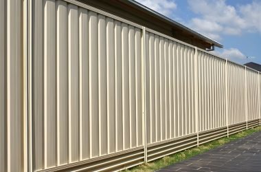 Steel plinth retaining wall supporting a cream steel privacy fence